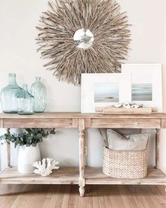 a wooden table topped with vases and pictures next to a wall mounted sunburst