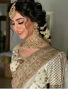 a woman in a white and gold bridal gown with jewelry on her head, smiling