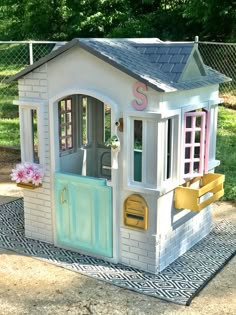 a toy house with the door open and windows painted pink, yellow and blue on it's side