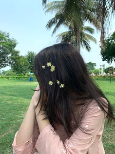 the back of a woman's head with three daisies pinned to her hair