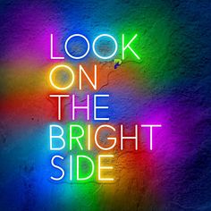 the words look on the bright side are lit up against a wall with multicolored lights