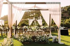 an outdoor wedding set up with white draping and flowers