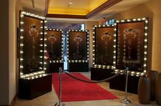 a red carpeted hallway with lighted mirrors and lights on the walls, along with a red carpet