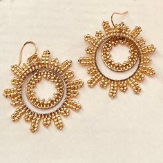 two pairs of earrings with gold beads on them sitting on top of a white surface