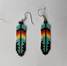 a pair of earrings made out of seed beads on a white surface with a black bead hook