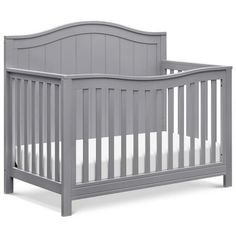 a gray crib with white sheets on it