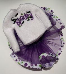 a white sweater with purple and green polka dot tulle on top of a plate