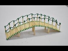 a miniature wooden bridge made out of toothpicks with green stringing on it