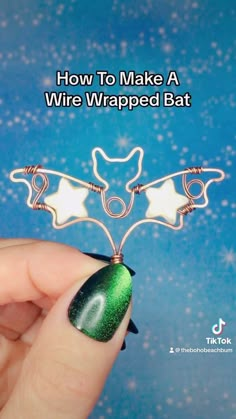 a hand holding a wire wrapped bat with green and white designs on it's wings