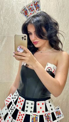 a woman is taking a selfie with her cell phone and playing cards in front of her