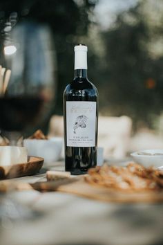 a bottle of wine sitting on top of a table next to some food and glasses