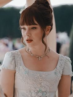 a woman in a white dress wearing a necklace