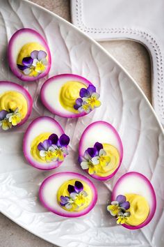 deviled eggs decorated with edible flowers on a plate