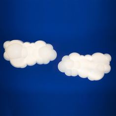 two white clouds floating in the air on a blue background