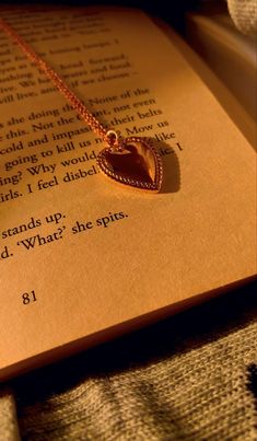 an open book with a heart pendant on it