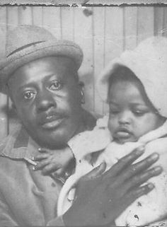 an old black and white photo of a man holding a small child in his arms