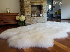 a large white sheepskin rug in front of a fireplace