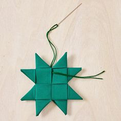 the origami star is made out of green paper and has a needle in it