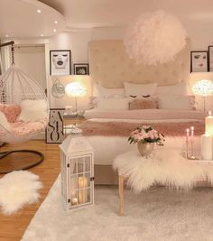 a bedroom decorated in white and pink with feathers on the bed, chandelier