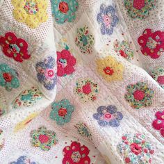 a close up of a quilt on a bed with flowers and polka dotty fabric