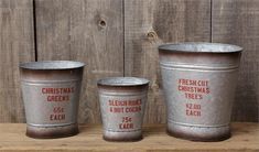 three metal buckets sitting on top of a wooden table next to eachother