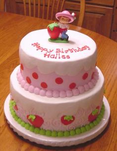 a three tiered birthday cake on a wooden table