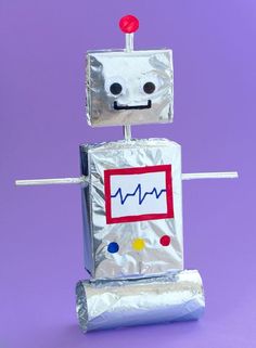 a robot made out of tin foil with a red button on it's head