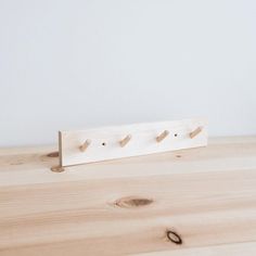 a wooden shelf with three pegs on it and a white wall in the background