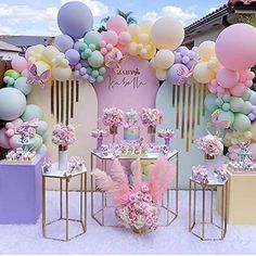 a pink and blue party with balloons, flowers, and desserts on the table