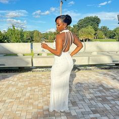 a woman in a white dress standing on a brick walkway