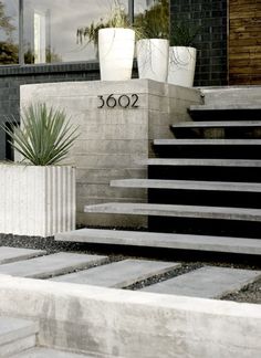 two white planters sitting on top of cement steps