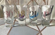 four glasses with different designs on them sitting next to each other in front of a wall