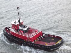 a red tug boat traveling through the water