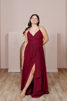 a woman in a blue dress standing on a wooden floor with her arms behind her back