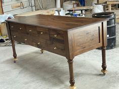 a wooden table with drawers on it in a room filled with other furniture and tools