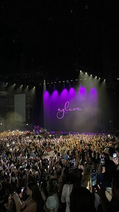 a large group of people standing on top of a stage with cell phones in front of them