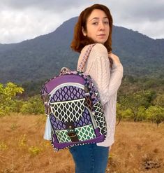 a woman is standing in the grass with a backpack