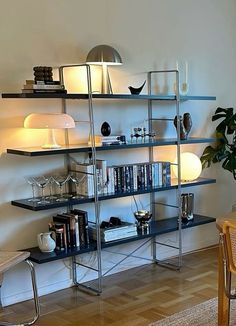 a living room filled with furniture and a book shelf next to a wall mounted lamp