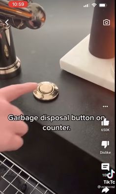 someone is pointing to the button on their computer keyboard that says garbage disposal button on counter