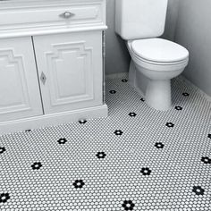 a white toilet sitting next to a sink in a bathroom under a vanity with black and white tiles