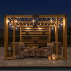 a wooden pergolan with string lights on the top and two chairs under it