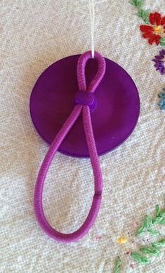 a purple object with a string attached to it sitting on a white cloth covered table