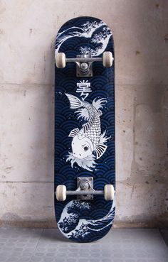 a skateboard with an image of a fish on it's back end is hanging up against a wall