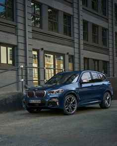 a blue bmw suv parked in front of a building