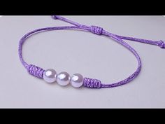 two white pearls are attached to a purple string with silver beads on the end of it