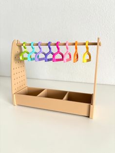 a wooden rack with several pairs of colorful clothes hanging from it's hooks on a white wall