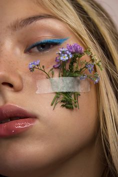 a woman with blue makeup and flowers on her face is looking at the camera while she has