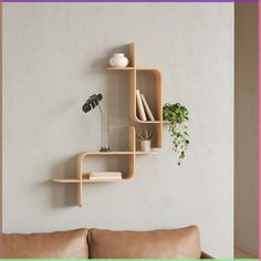 a living room scene with focus on the sofa and shelves that have books, plants, and vases