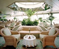 an indoor restaurant with wicker furniture and potted plants on the tables in front of them