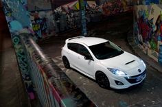 a white car parked next to a graffiti covered wall